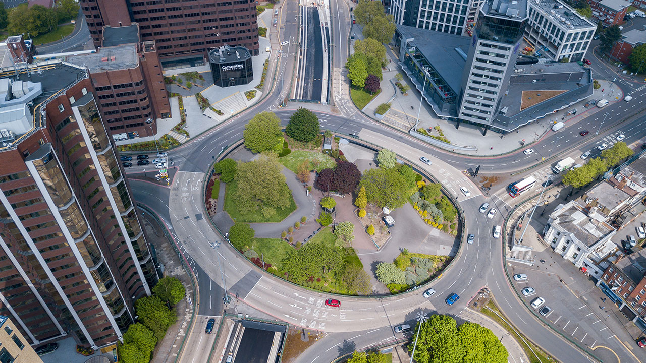 Large roundabout road system viewed from above, with green grass in the middle