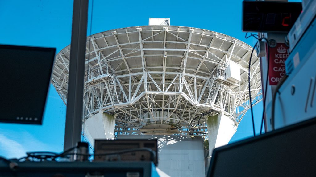 White radar dish with metal supports, viewed through window