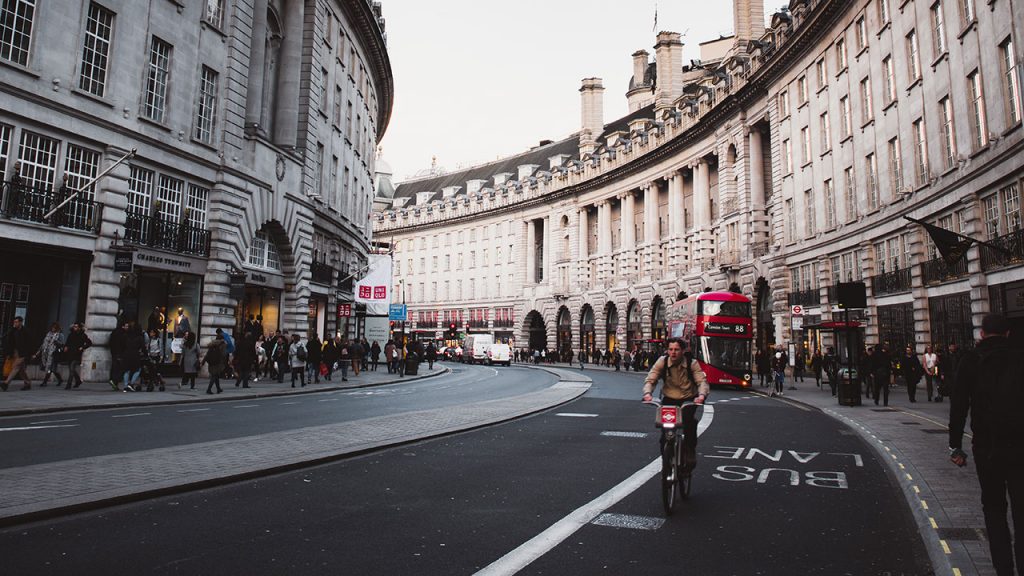 Cyclist travels on empty road, historic white buildings line the streets