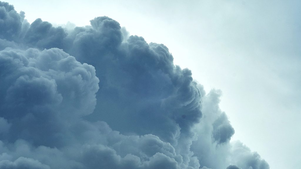 Large fluffy, dark cloud in a blue and white sky.