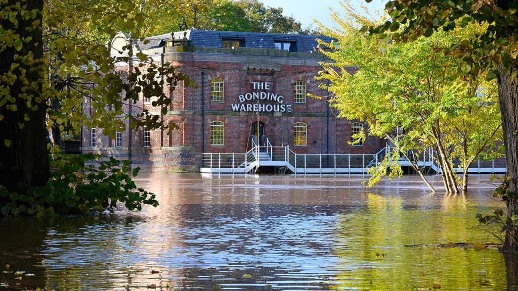 Square red brick building surrounded by high levels of water