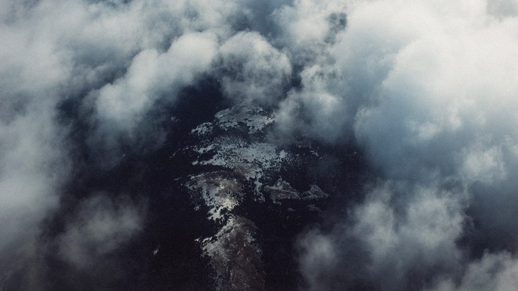 Fluffy white clouds frame an aerial view of islands below.