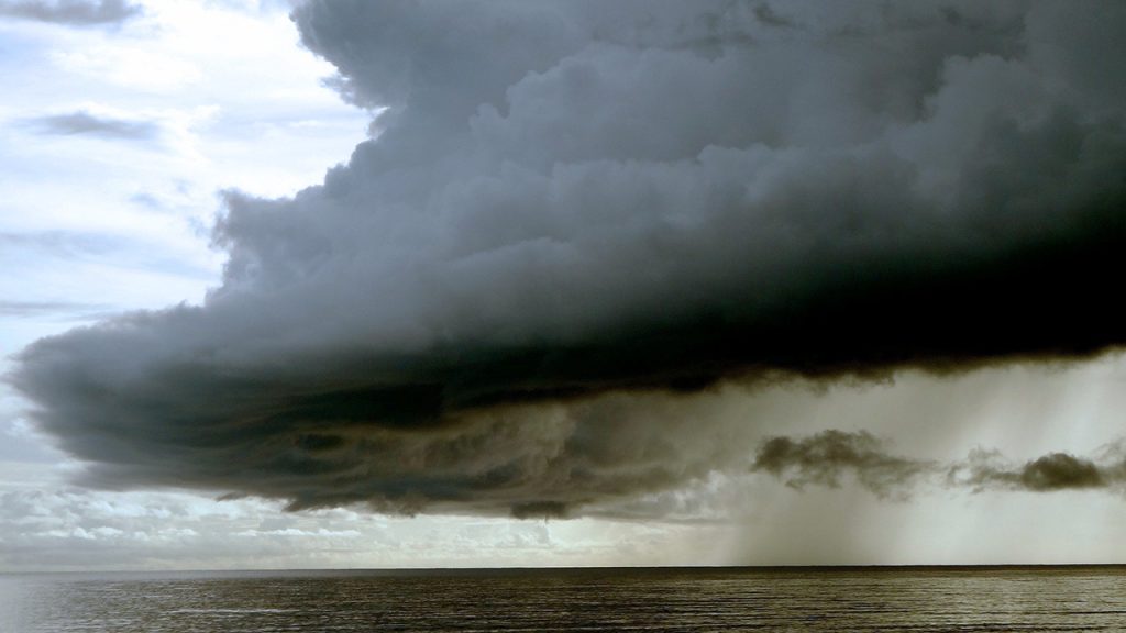 Large, dark cloud looms over the sea.