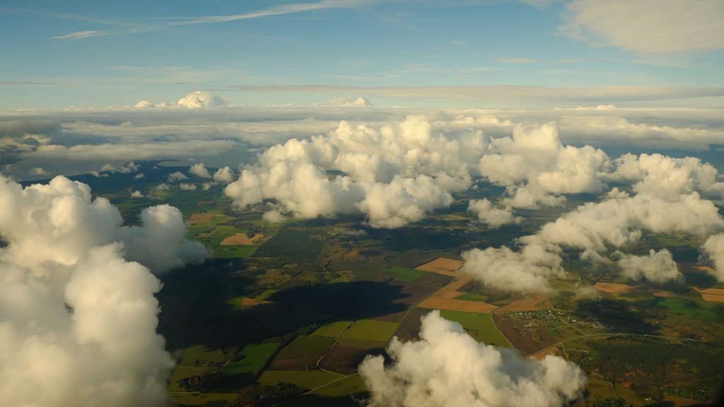 Fluffy, white clouds above green and yellow fields