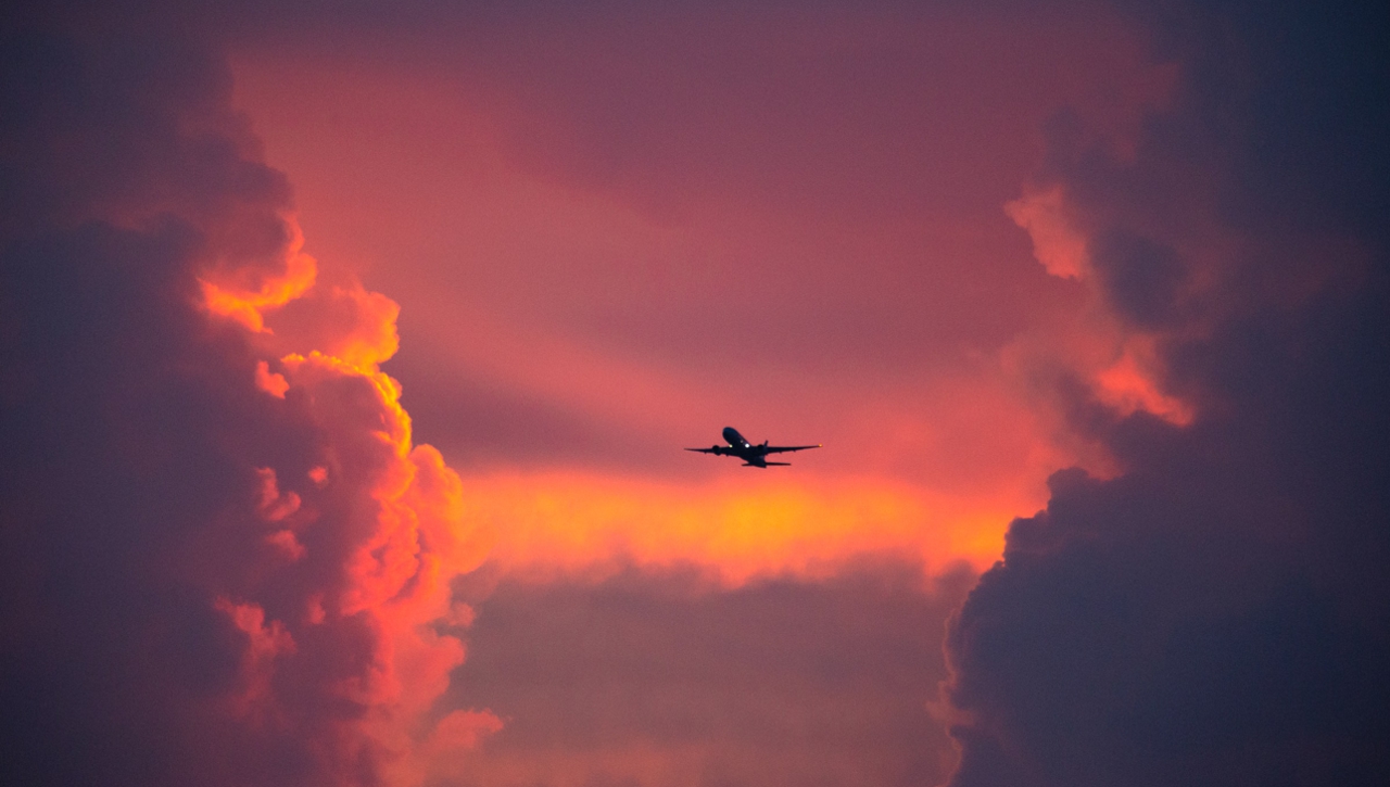 Airplane flying through red hazy clouds