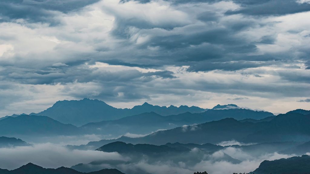 Grey clouds loom over silhouetted mountains