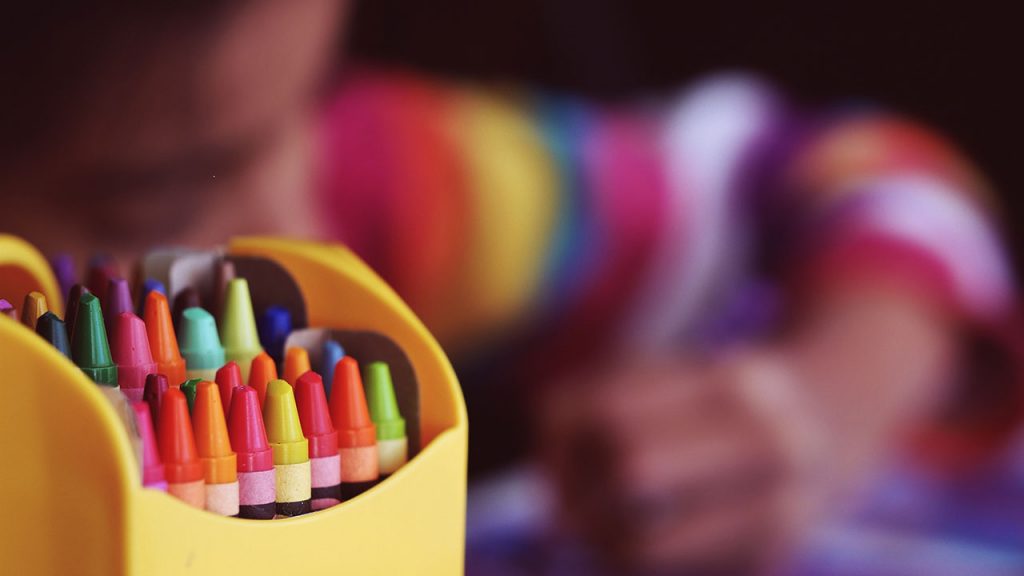 Multi-coloured crayons inside a yellow tub