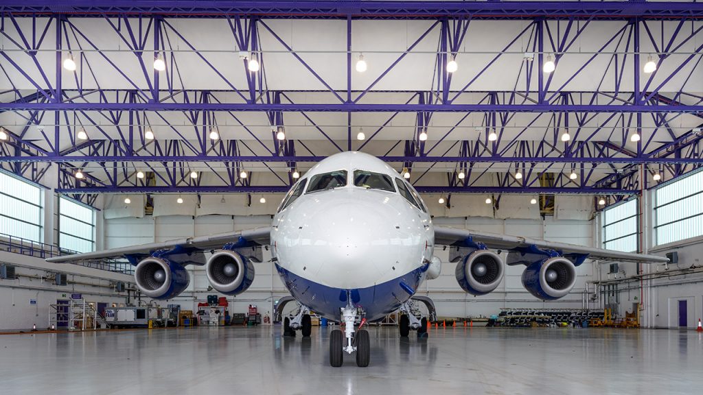 Front view of a large, white aircraft inside a large hangar