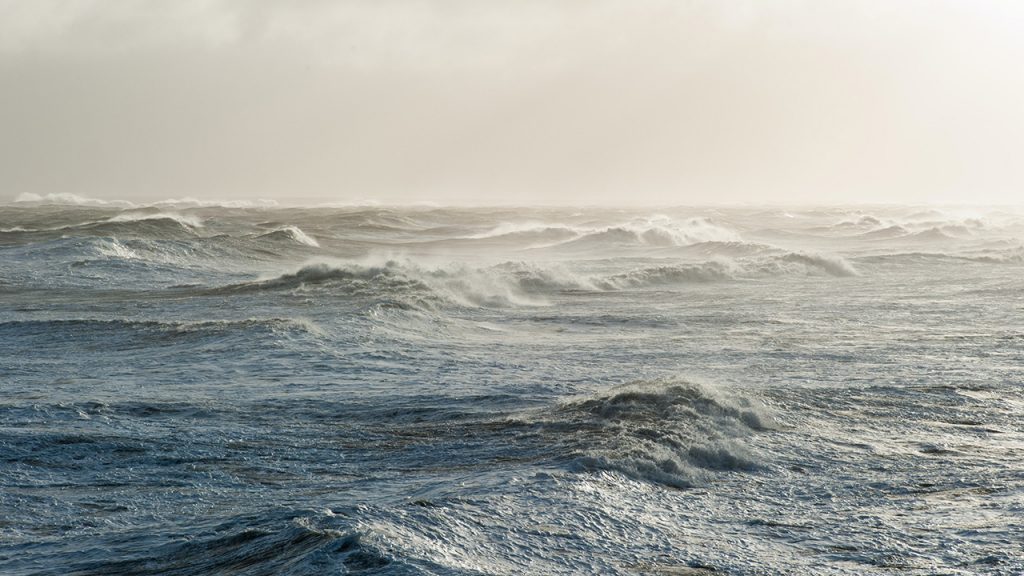 Ocean waves beneath a hazy, clear horizon