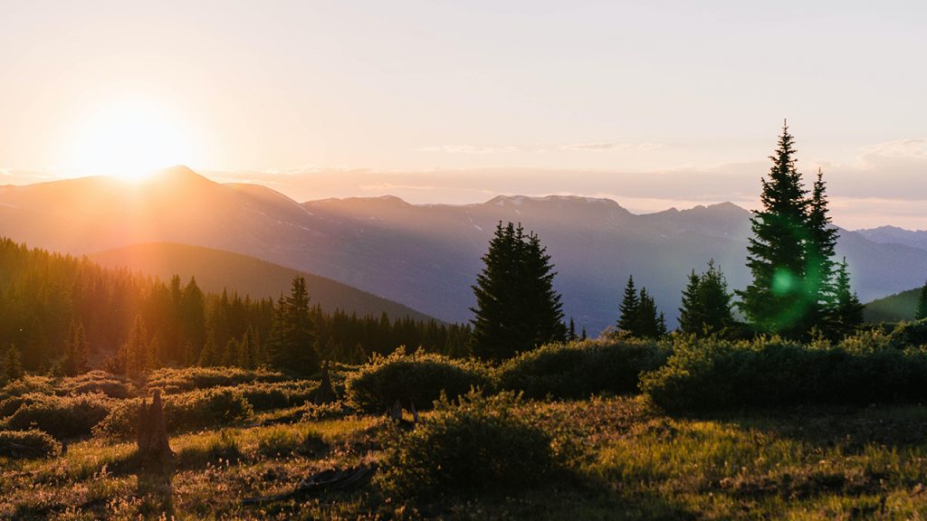 Sun sets behind a green, rolling landscape