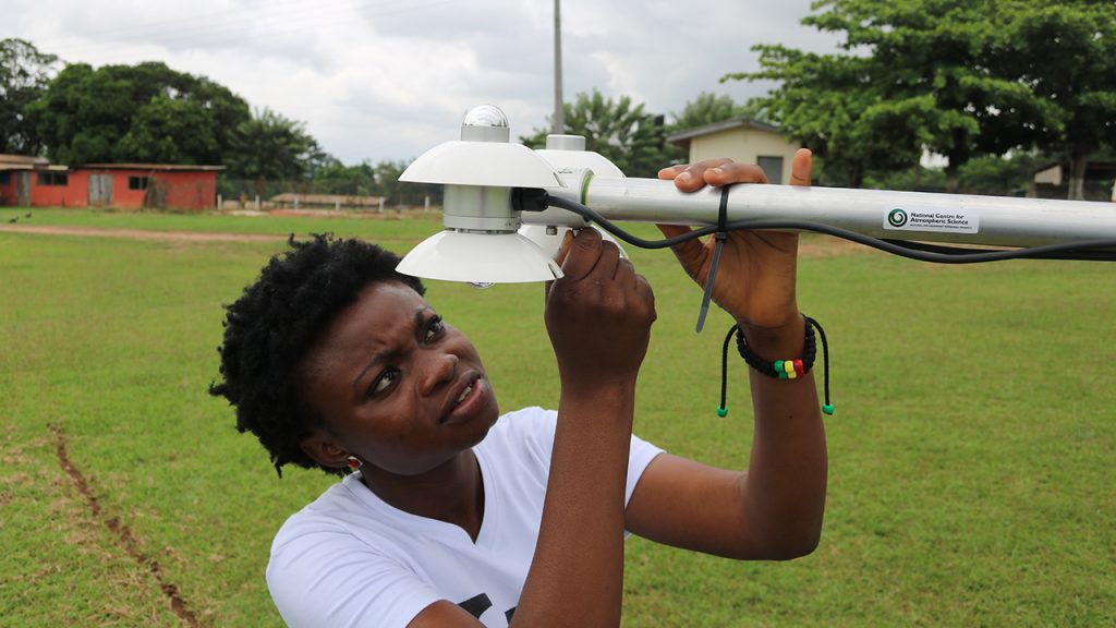 Person inspects scientific instrument in a grass field