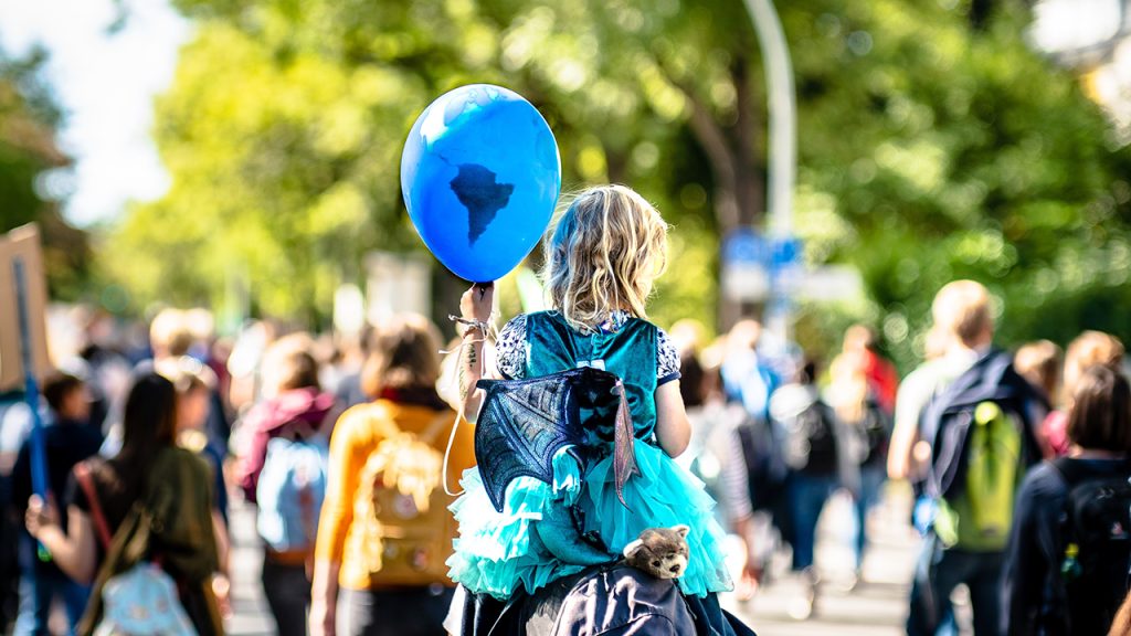 Young person holds balloon decorated as Earth