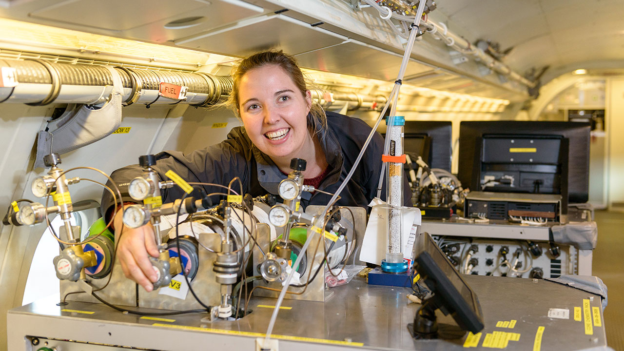 Person stands inside aircraft, operating scientific instrumentation