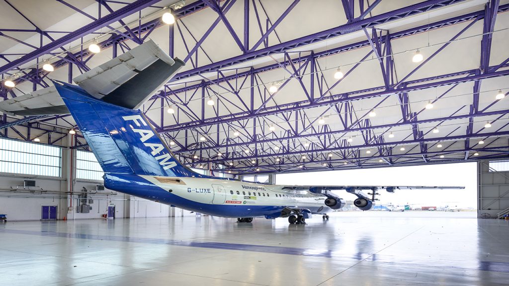 The rudder and vertical stabiliser of a blue and white aircraft inside a hangar