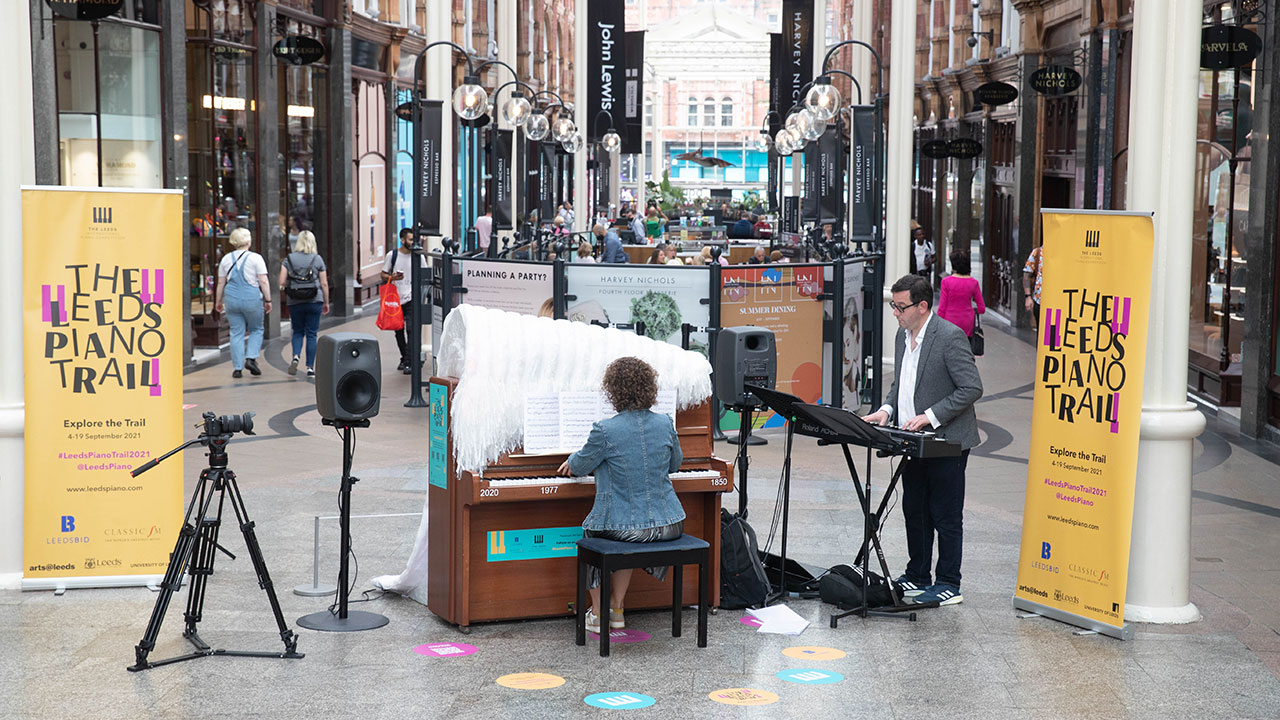 Pianist plays decorated piano in shopping centre