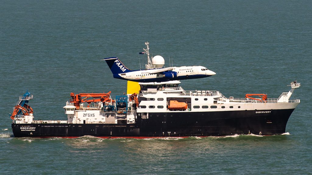 Research aircraft flies past research ship in open waters