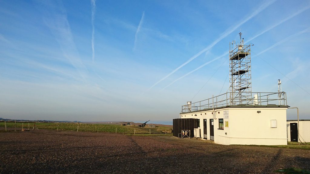 A low white observatory building and a large blue sky