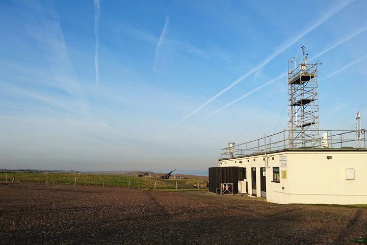 A low white observatory building and a large blue sky