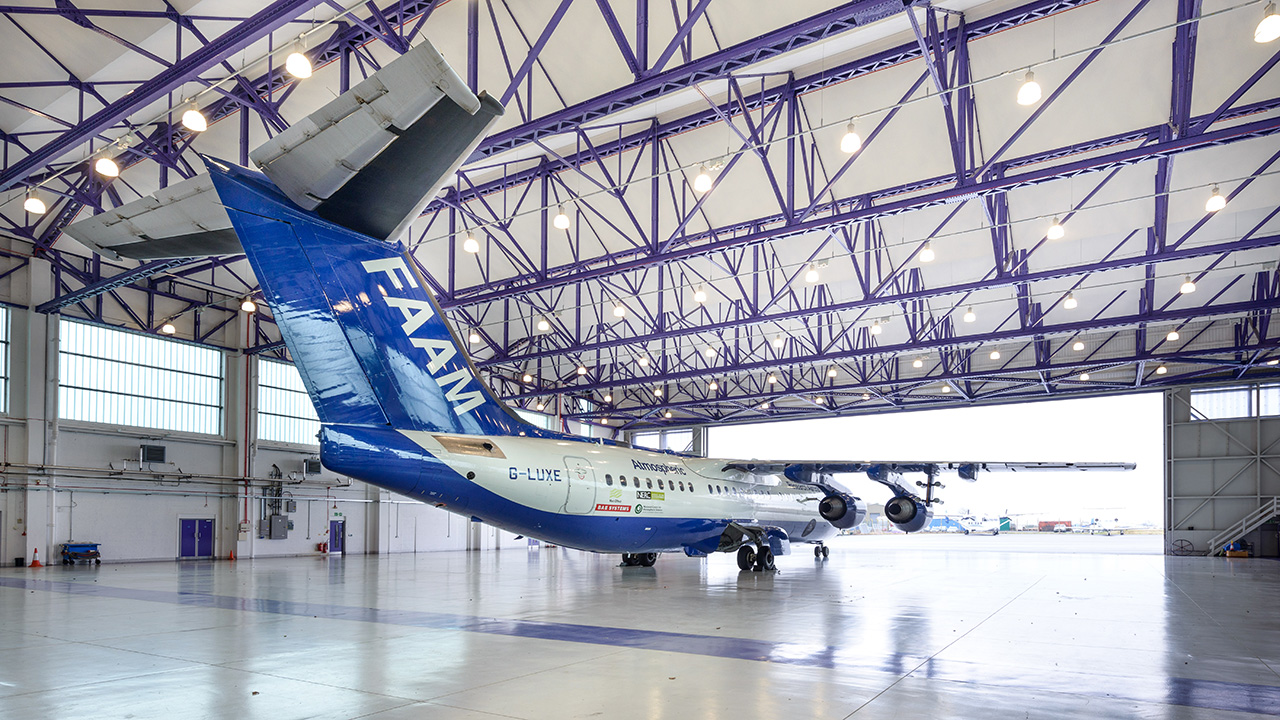 Blue and white aircraft with the word FAAM on the tail, inside an aircraft hangar
