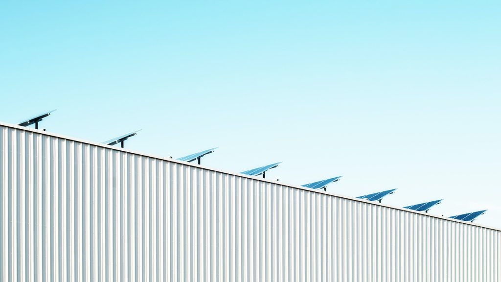 solar panels on a grey corrugated factory building and a blue sky