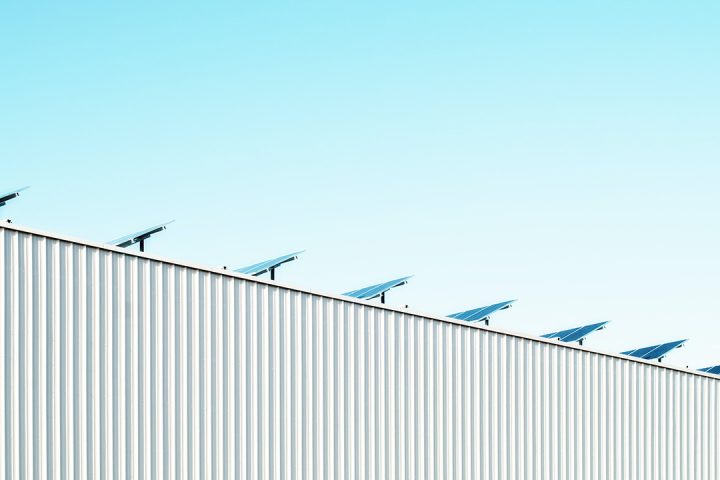solar panels on a grey corrugated factory building and a blue sky