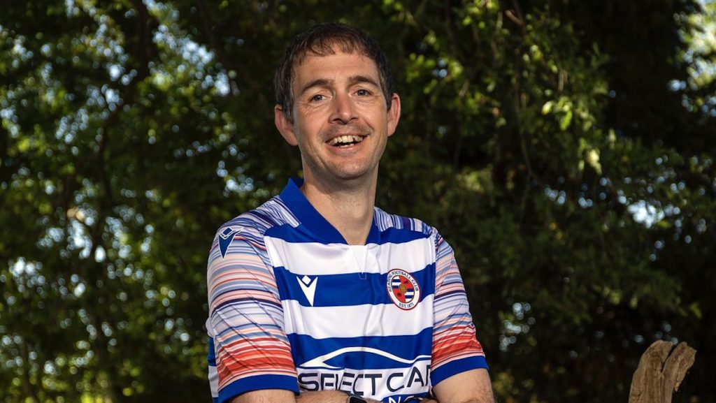 Professor Ed Hawkins wears a blue and white striped Reading Football Club shirt, featuring red and blue hoops on each sleeve.