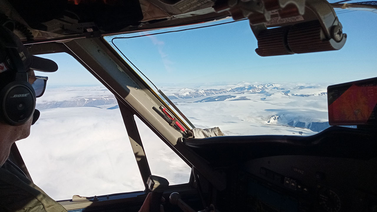 Pilot looks out of cockpit towards a sheet of Arctic sea ice