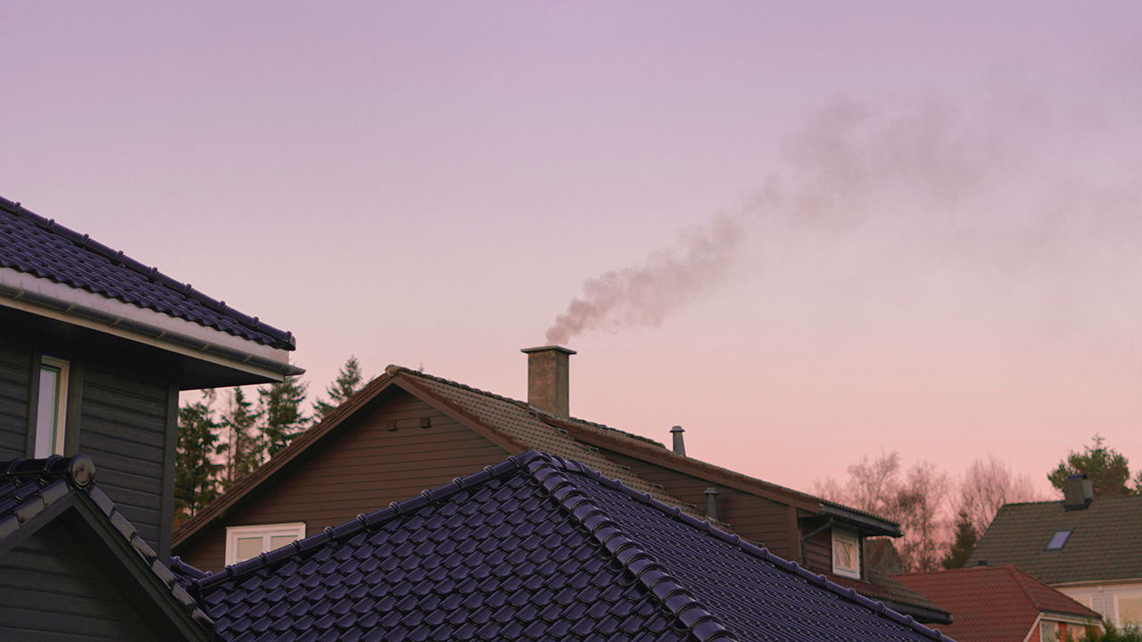Smoke rises from a chimney on house rooftop