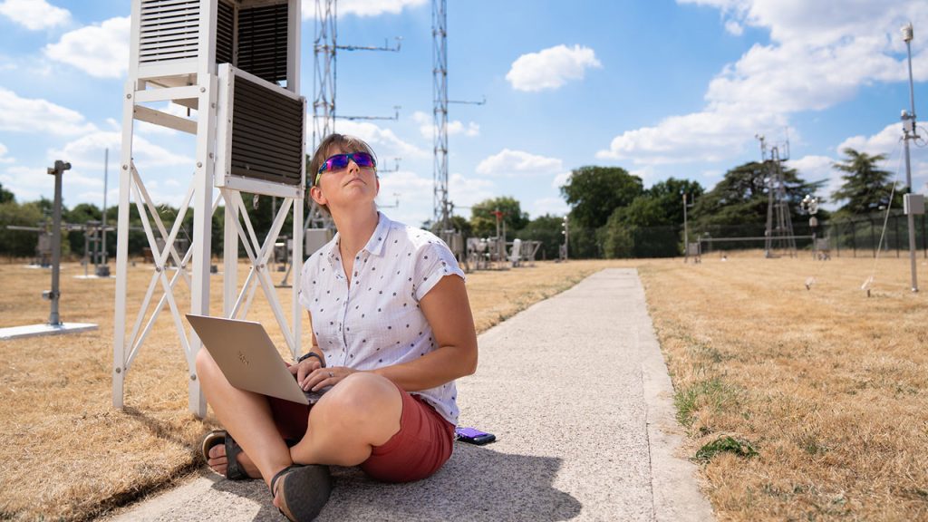 Woman sat crossed legged on the ground outside in an observations field.