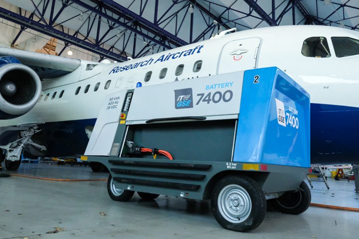 An electric ground power unit plugged in next to a white and blue aircraft