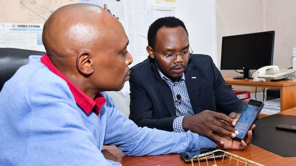 Two scientists looking at a weather app on a smart phone.