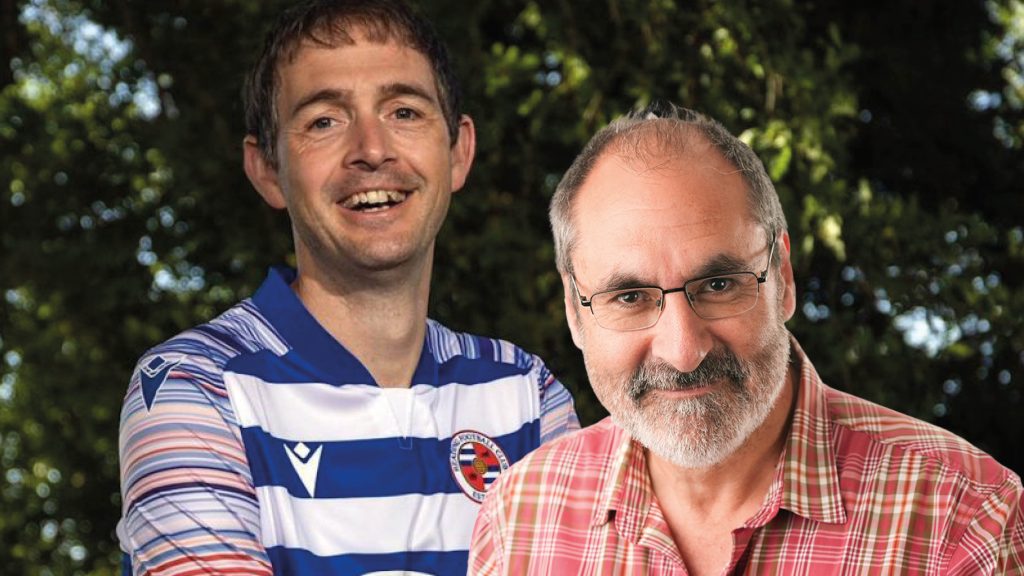 Two men side by side, one is wearing a blue striped tshirt and the other is wearing a red checked shirt and glasses.