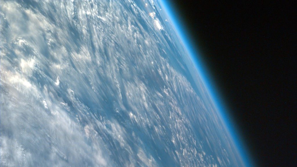 A view of the Earth and its atmosphere from space, with a blue glowing band against a black background.