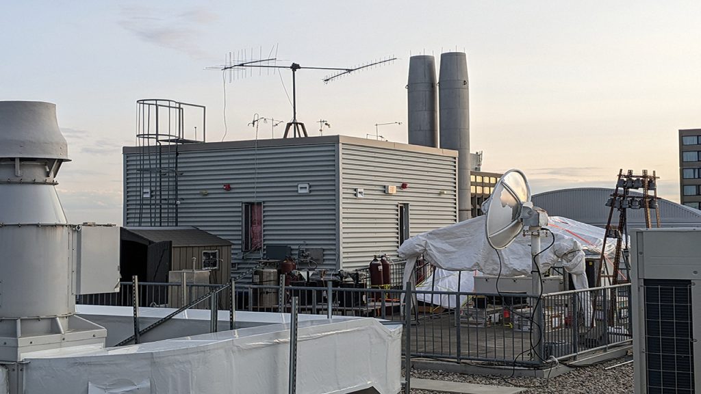 Scientific equipment on top of rooftop. Hazy sky in background.