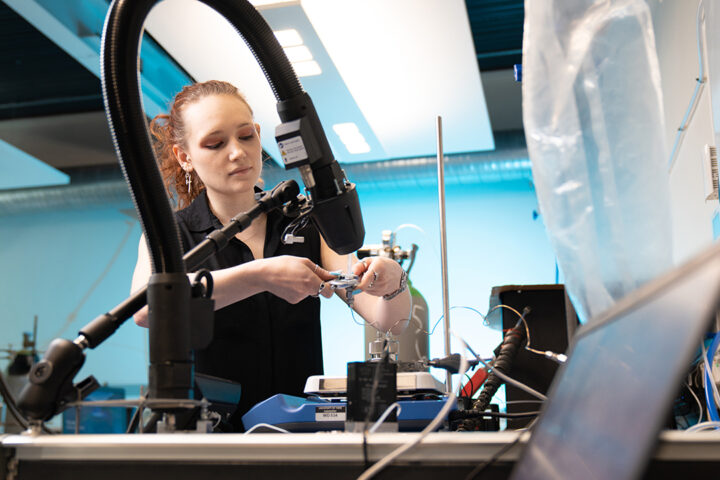 Person wearing black shirt holds adjustable wrench in a laboratory