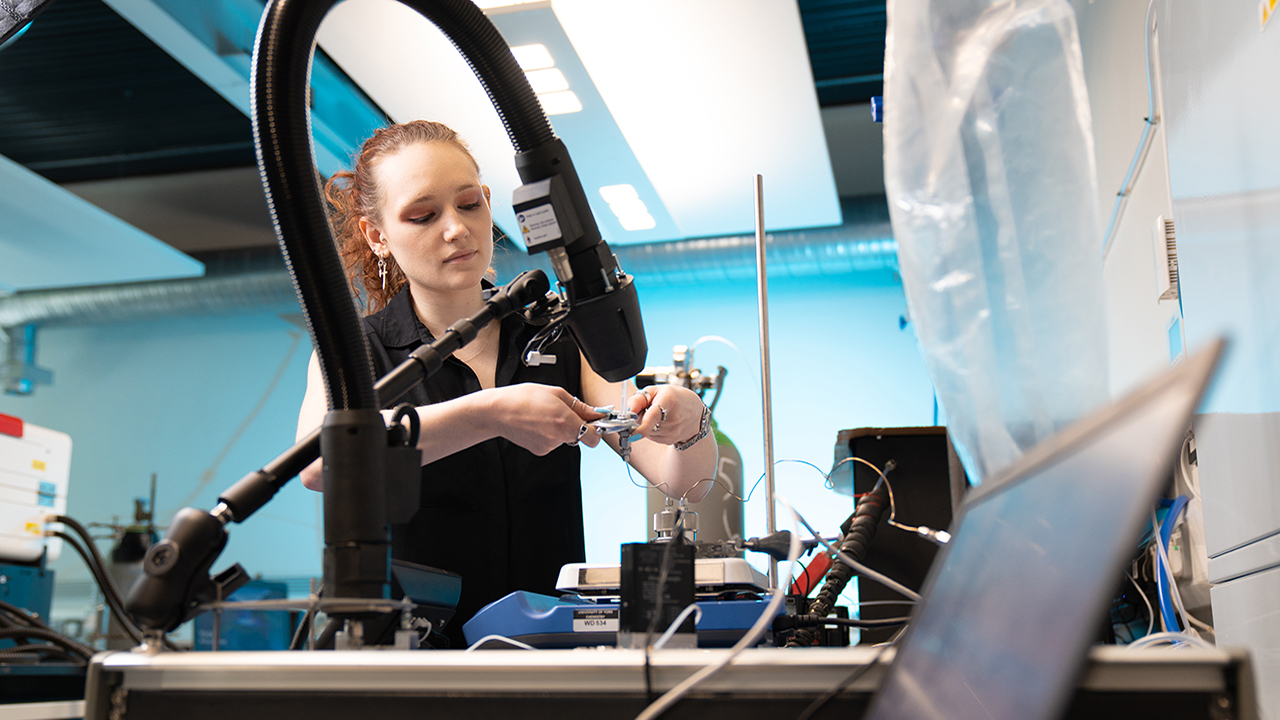 Person wearing black shirt holds adjustable wrench in a laboratory