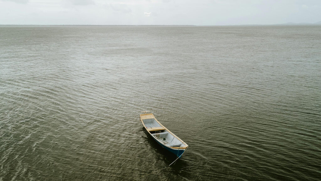 A small empty fishing boat on a large body of water in south america