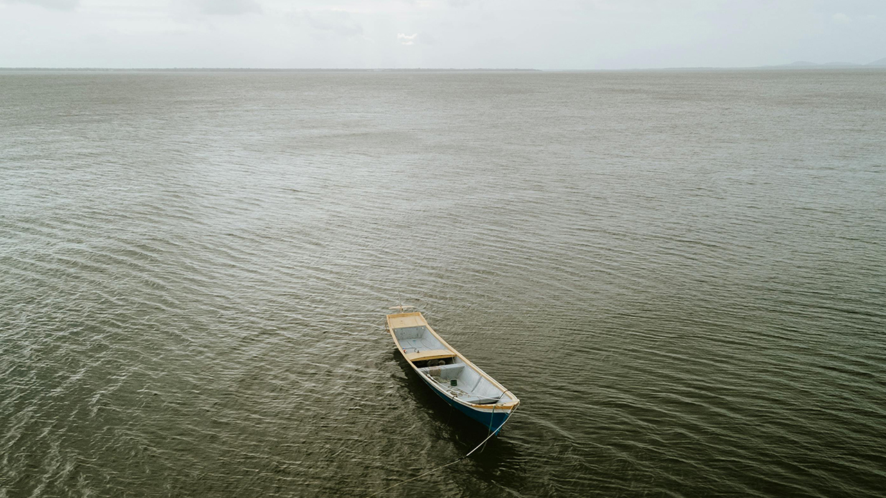 A small empty fishing boat on a large body of water in south america