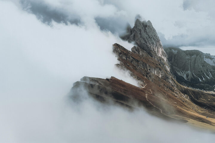 White clouds push up against the crest of a mountain