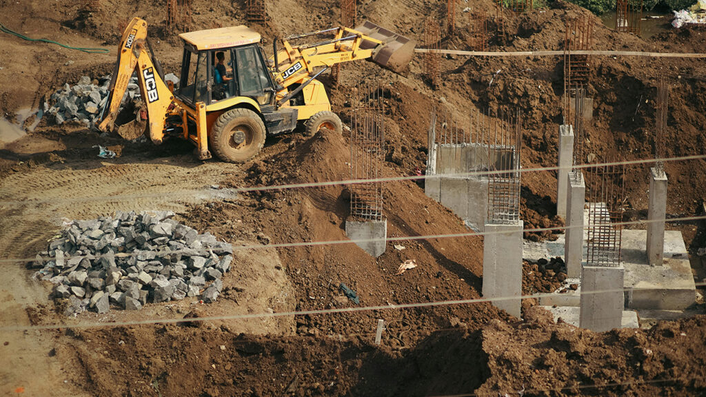 JCB digger perched on a flattened mound of earth at a construction site