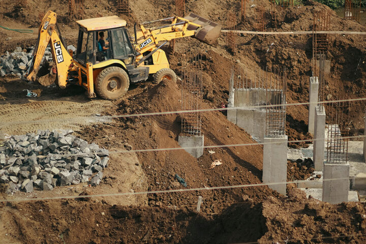 JCB digger perched on a flattened mound of earth at a construction site
