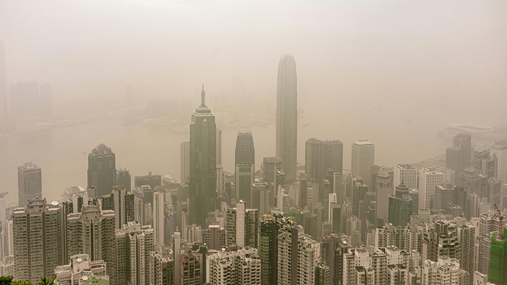 skyscraper buildings rising up into thick polluted air and cloud