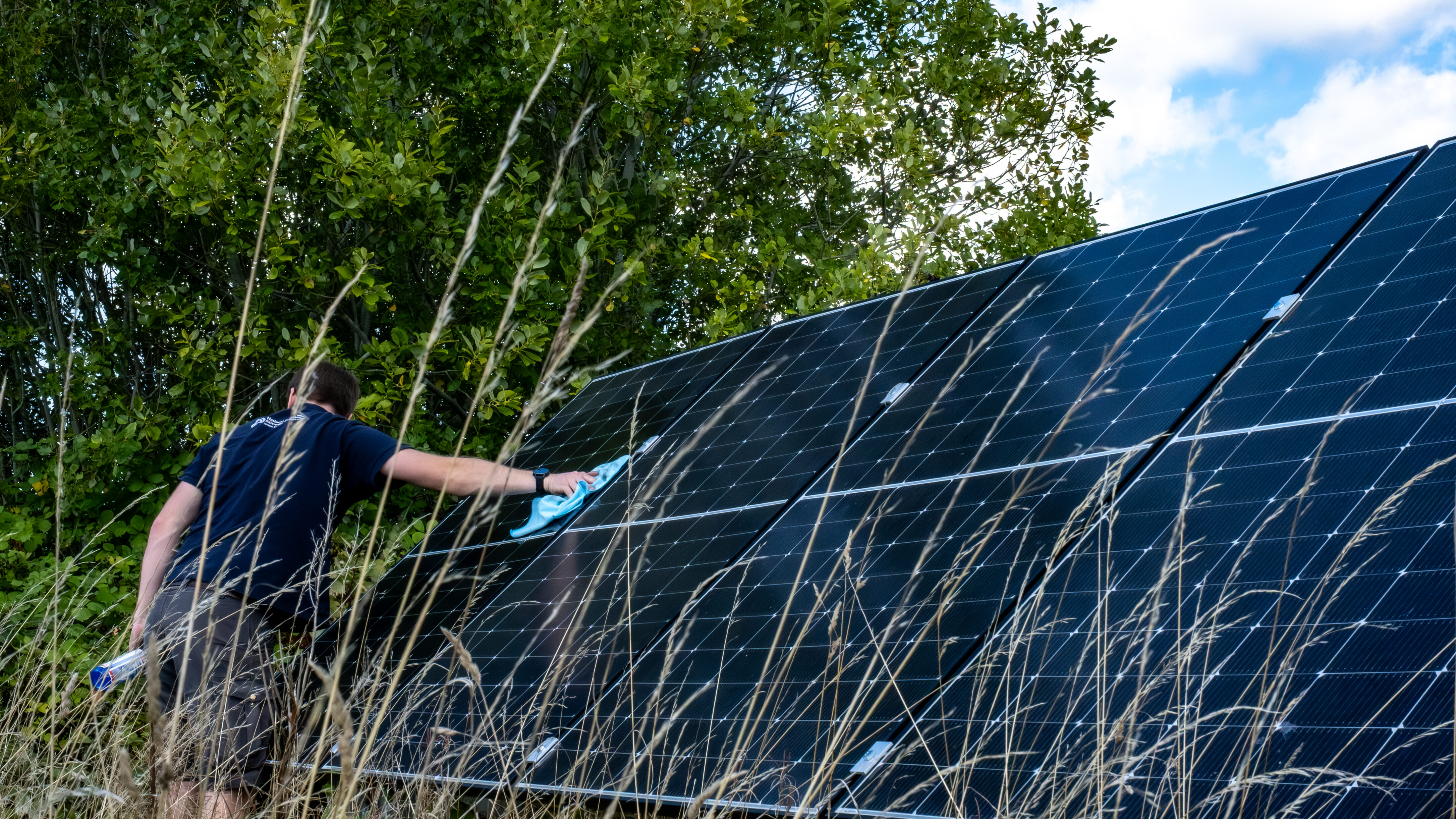 Person using a cloth to clean solar panels in a field