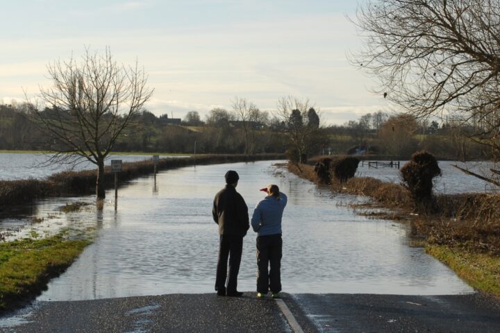 Two people looking at a road flooded by the River Avon