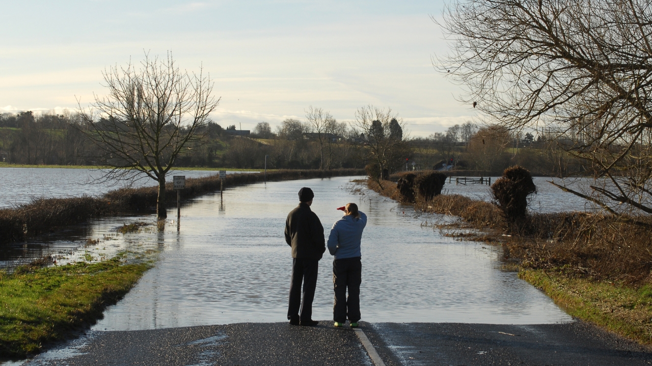Two people looking at a road flooded by the River Avon
