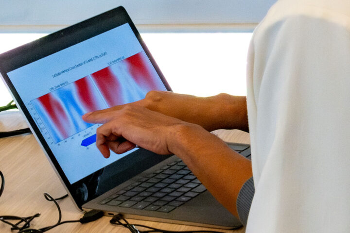 A person points with both of their hands to a red and blue graph on their computer screen.