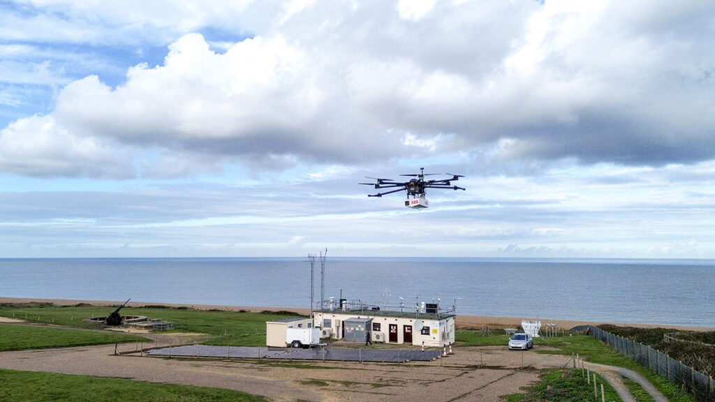 A drone flies up above a building that is situated on a coastline