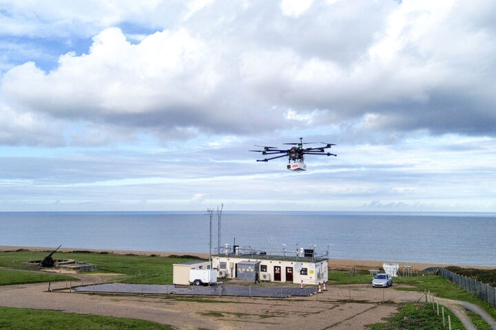 A drone flies up above a building that is situated on a coastline