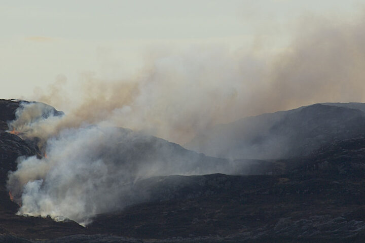 smoke billowing from a dark moorland landscape