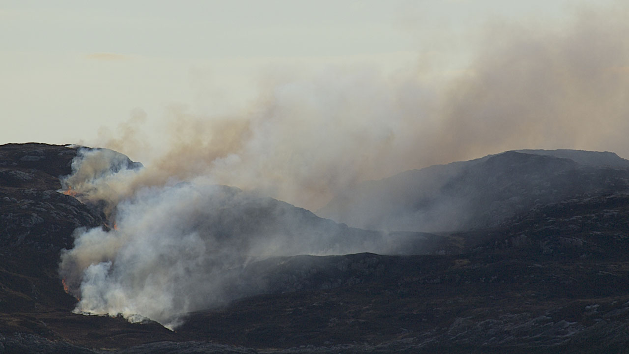 smoke billowing from a dark moorland landscape